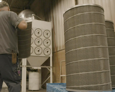 A worker headed towards an indusrial dust collector to replace cartridge filters.