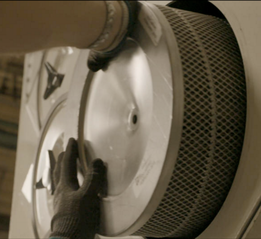 Machine operator replacing dust collector cartridge filters in an industrial facility.